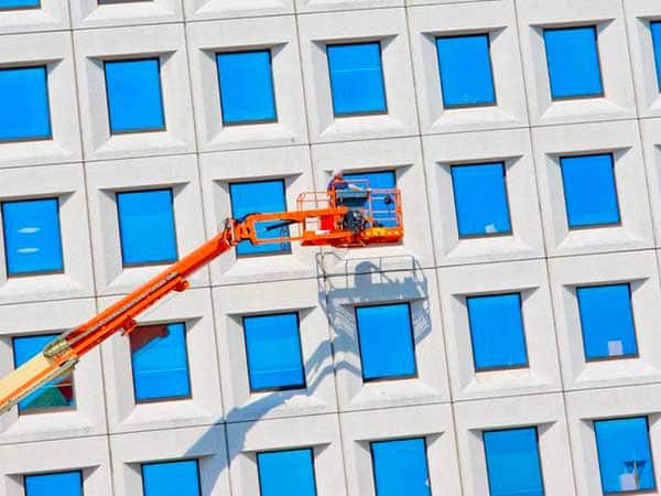 21534032 - worker cleaning high tower with blue glass Impresa-pulizia-finestre-esterne-parma